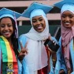 Three graduates smile for a photo in cap and gown